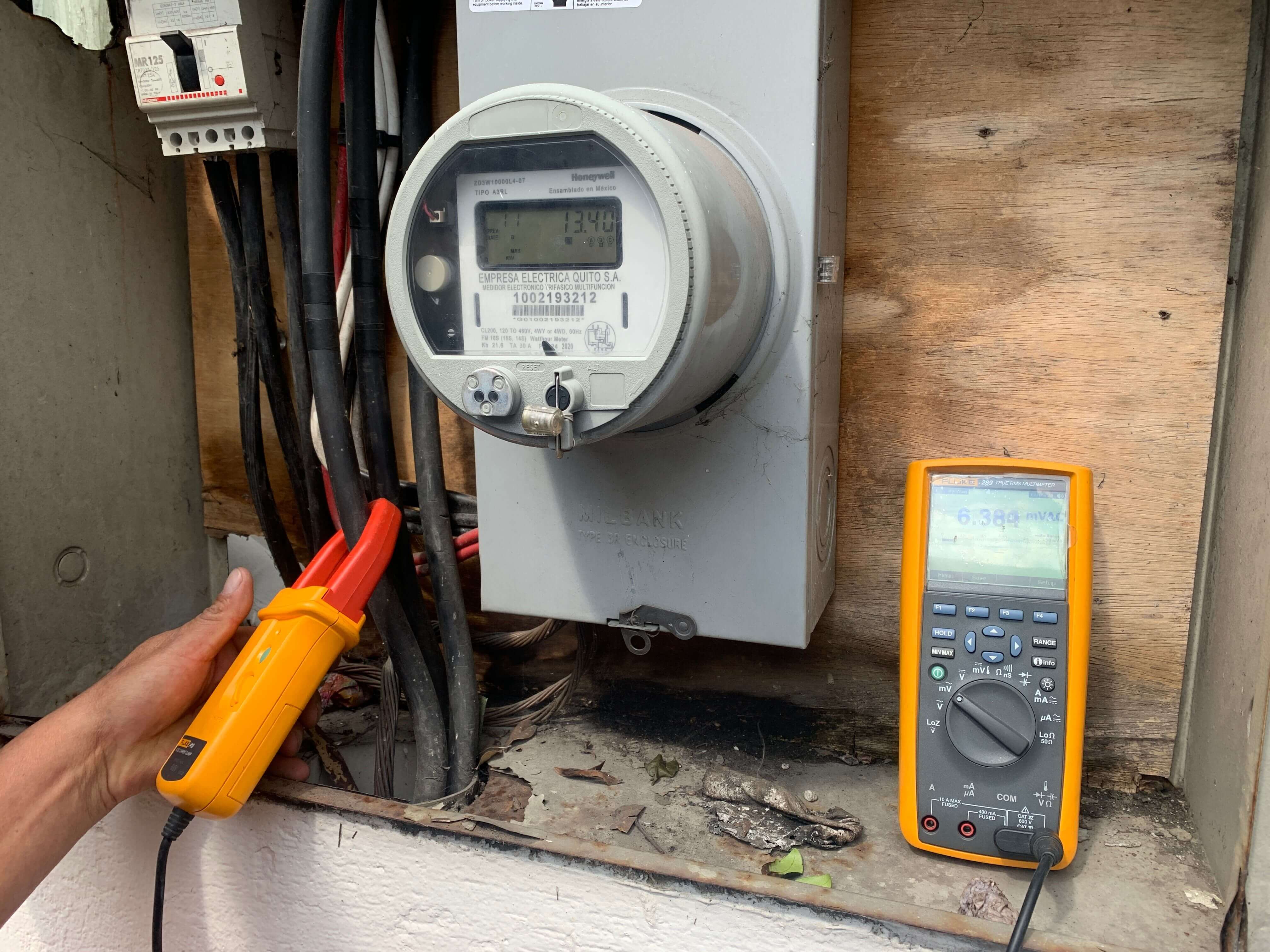 Medición de parámetros eléctricos en medidor residencial utilizando multímetro profesional durante diagnóstico técnico